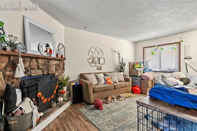 living room with a textured ceiling, hardwood / wood-style flooring, and a fireplace