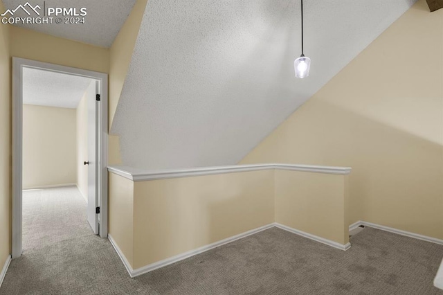 hall with a textured ceiling, lofted ceiling, and light carpet