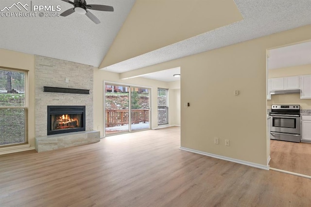 unfurnished living room with light wood-type flooring, a textured ceiling, a fireplace, high vaulted ceiling, and ceiling fan