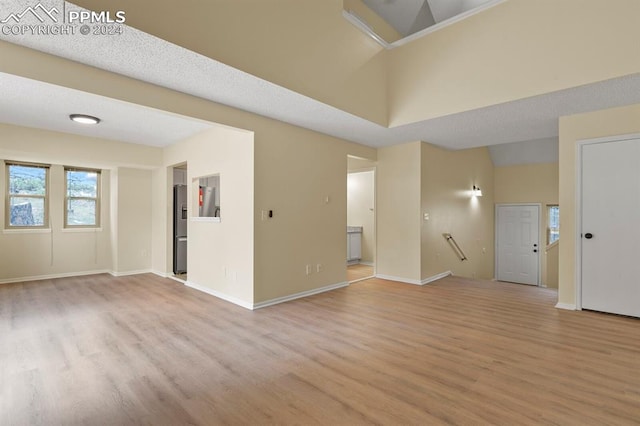 empty room with light wood-type flooring and a textured ceiling