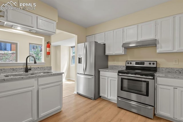 kitchen with appliances with stainless steel finishes, light hardwood / wood-style floors, sink, and white cabinets