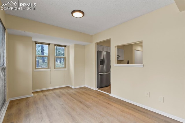 spare room with a textured ceiling and light hardwood / wood-style floors