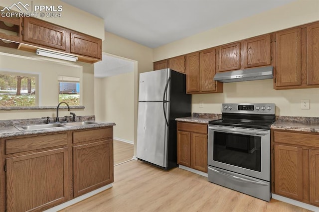 kitchen with appliances with stainless steel finishes, sink, and light hardwood / wood-style flooring