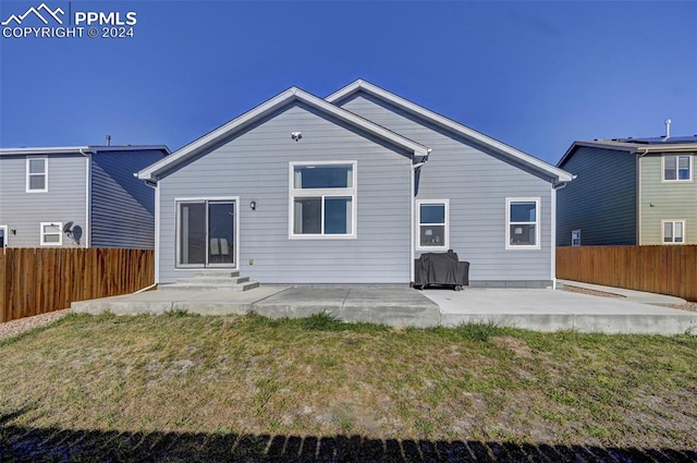 rear view of house with a patio and a lawn