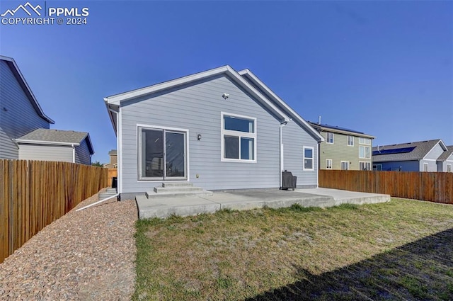 back of house with a lawn and a patio