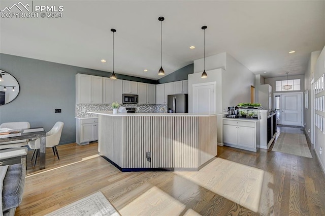 kitchen with light hardwood / wood-style floors, white cabinets, pendant lighting, stainless steel appliances, and a center island with sink