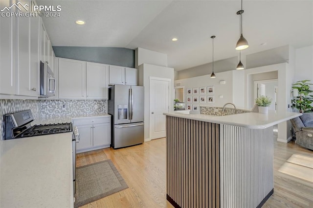 kitchen with lofted ceiling, decorative light fixtures, white cabinetry, stainless steel appliances, and light hardwood / wood-style floors