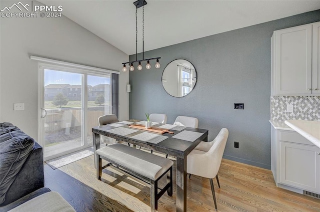 dining room with vaulted ceiling and light hardwood / wood-style flooring