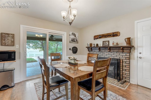 dining room with a brick fireplace, light wood-type flooring, and a chandelier