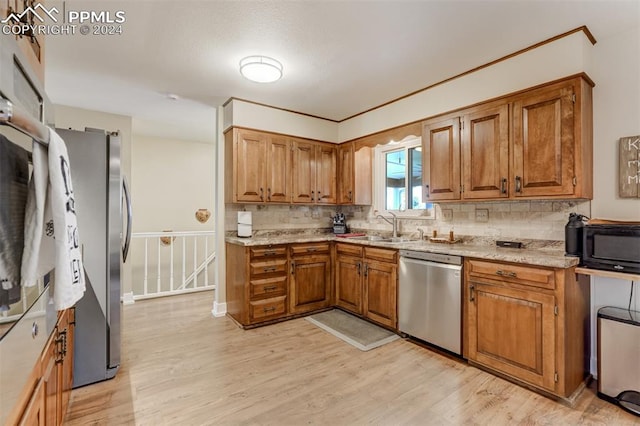 kitchen featuring sink, stainless steel appliances, light hardwood / wood-style floors, and tasteful backsplash