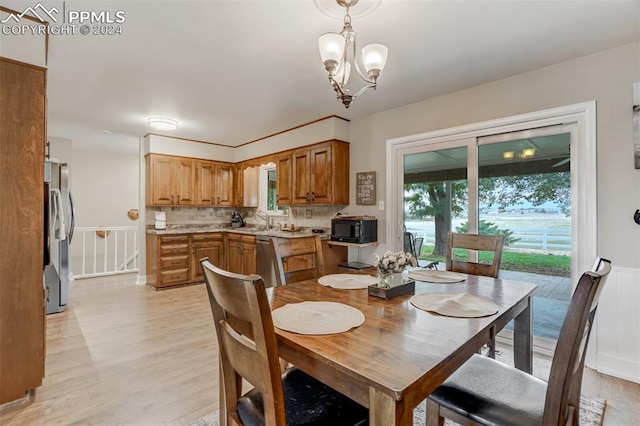 dining space with a notable chandelier, sink, and light hardwood / wood-style floors