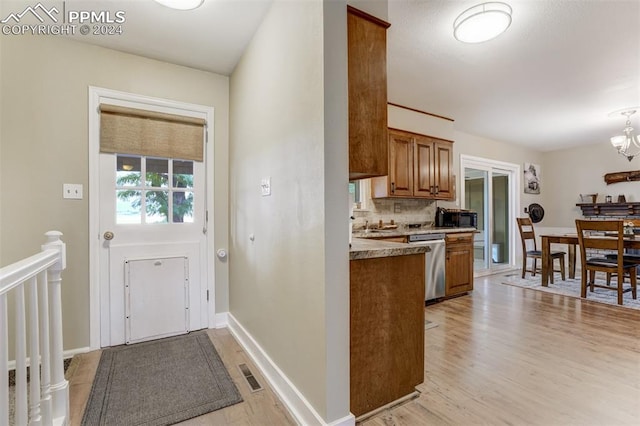 kitchen featuring a notable chandelier, light wood-type flooring, backsplash, and stainless steel dishwasher