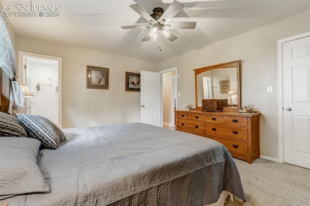 bedroom with ceiling fan, ensuite bath, and light carpet