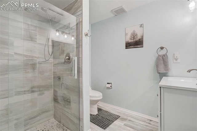 bathroom with wood-type flooring, a shower with door, vanity, and toilet