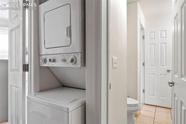 laundry area with stacked washer and clothes dryer and light tile patterned flooring