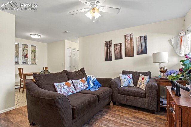 living room featuring ceiling fan, dark hardwood / wood-style flooring, and a baseboard heating unit