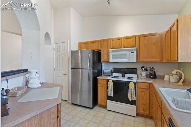 kitchen featuring white appliances, sink, and high vaulted ceiling