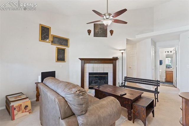 living room featuring vaulted ceiling, a tiled fireplace, ceiling fan, and light colored carpet