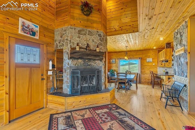 living room with wood walls, wood ceiling, a fireplace, and light wood-type flooring