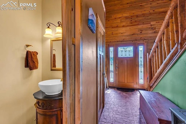 foyer with lofted ceiling, wood walls, sink, and wooden ceiling