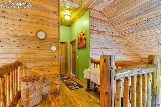 hallway with hardwood / wood-style floors, wooden walls, vaulted ceiling, and wood ceiling