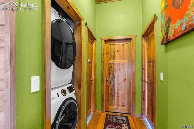 washroom featuring hardwood / wood-style flooring and stacked washing maching and dryer