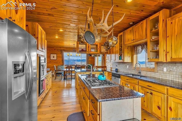 kitchen featuring decorative backsplash, sink, light hardwood / wood-style floors, appliances with stainless steel finishes, and a center island with sink