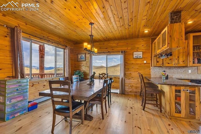 dining area featuring wood walls, a notable chandelier, light hardwood / wood-style flooring, and a mountain view