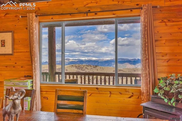 interior space with wood walls, a wealth of natural light, wood-type flooring, and a mountain view