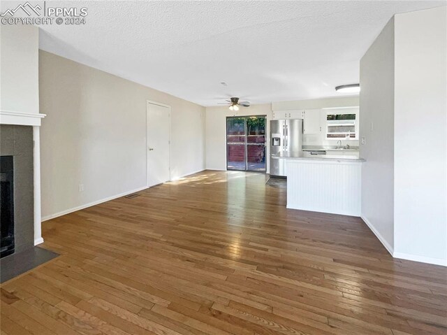 unfurnished living room featuring ceiling fan, a textured ceiling, dark hardwood / wood-style floors, and sink