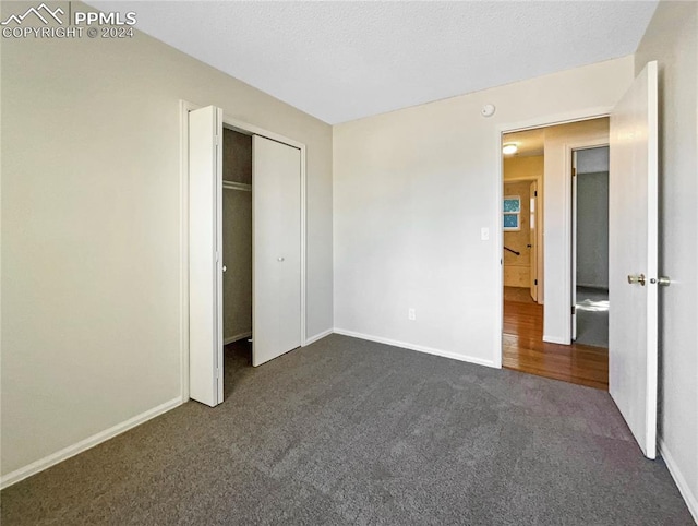 unfurnished bedroom featuring dark colored carpet, a closet, and a textured ceiling