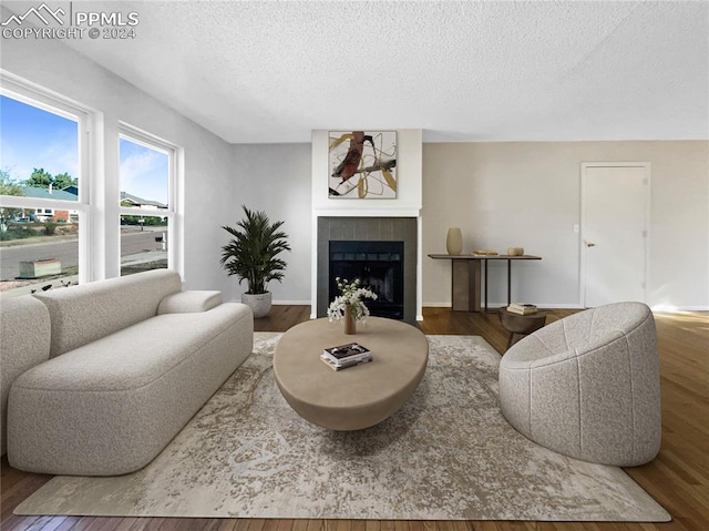 living room with a textured ceiling, a tile fireplace, and hardwood / wood-style flooring