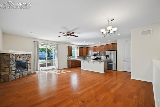 kitchen with a kitchen breakfast bar, pendant lighting, stainless steel appliances, wood-type flooring, and a center island