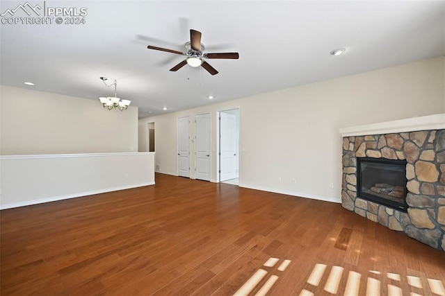 unfurnished living room with wood-type flooring, a fireplace, and ceiling fan with notable chandelier