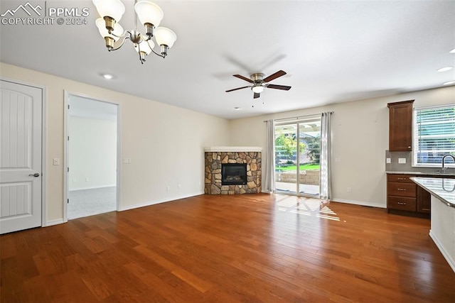 unfurnished living room with ceiling fan with notable chandelier, a fireplace, hardwood / wood-style floors, and sink