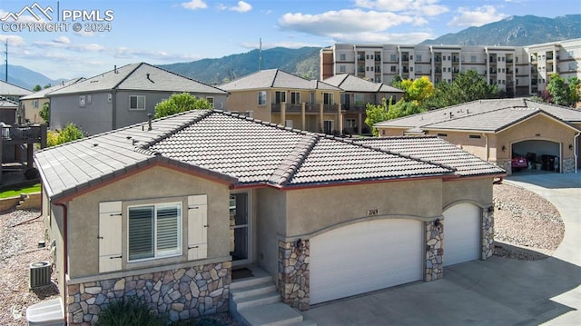 view of front facade featuring a garage, central air condition unit, and a mountain view