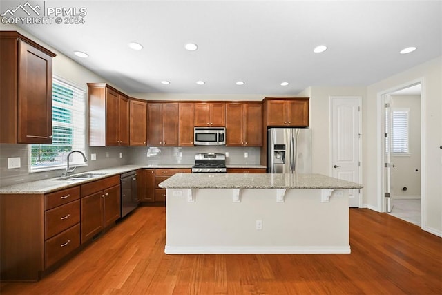 kitchen featuring appliances with stainless steel finishes, a breakfast bar, a kitchen island, wood-type flooring, and sink