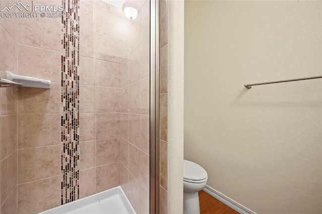 bathroom featuring hardwood / wood-style flooring, walk in shower, and toilet