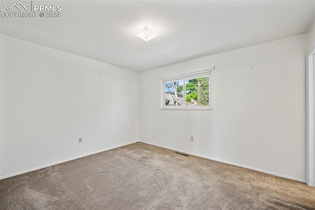 empty room featuring visible vents, baseboards, and carpet
