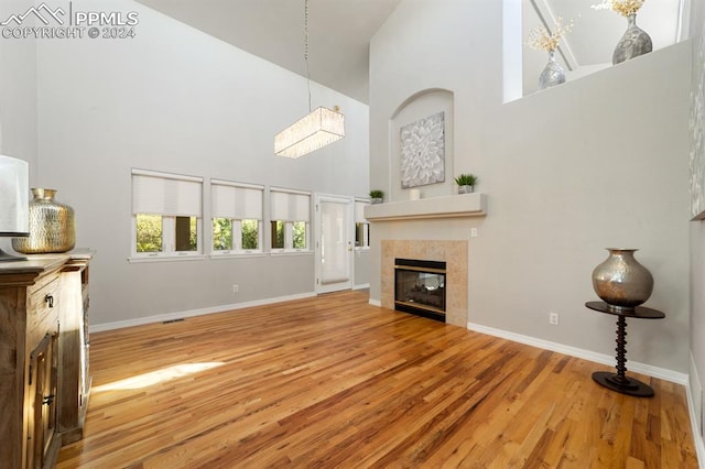 unfurnished living room with high vaulted ceiling, a fireplace, and hardwood / wood-style floors