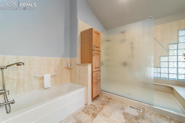 bathroom featuring tile walls, lofted ceiling, and plus walk in shower