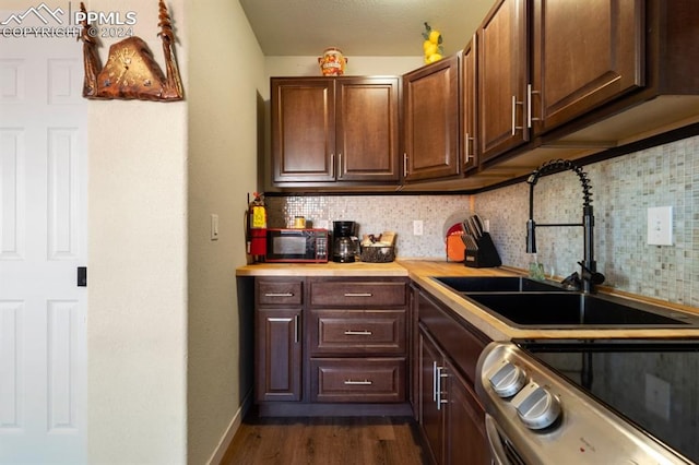 kitchen with decorative backsplash, sink, stove, and dark hardwood / wood-style floors