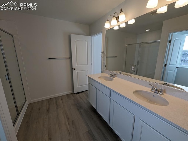 bathroom with hardwood / wood-style floors, vanity, and a shower with door