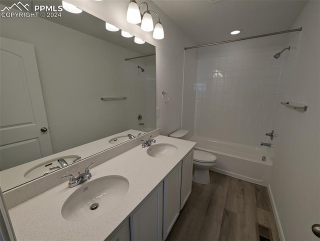 full bathroom with vanity, hardwood / wood-style floors, tiled shower / bath combo, and toilet