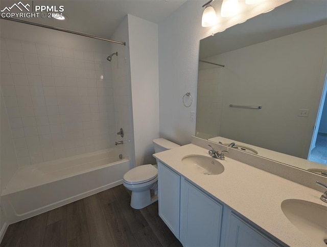 full bathroom featuring vanity, tiled shower / bath combo, hardwood / wood-style flooring, and toilet