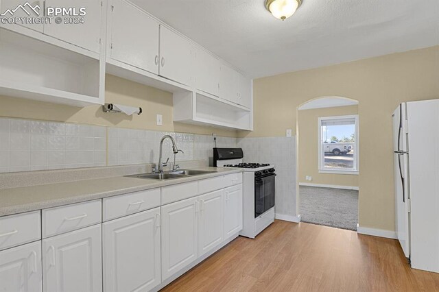 kitchen featuring white appliances, sink, light hardwood / wood-style flooring, and white cabinets