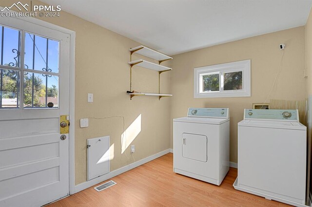 washroom with light hardwood / wood-style flooring, plenty of natural light, and washer and dryer