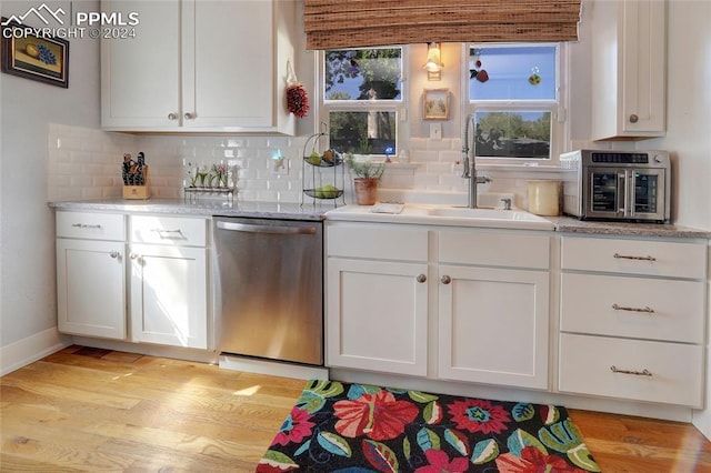 kitchen featuring light wood-type flooring, dishwasher, sink, white cabinets, and backsplash