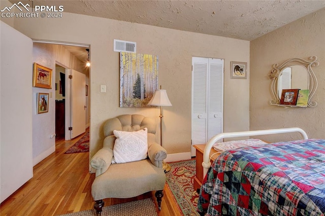 bedroom featuring a textured ceiling, light hardwood / wood-style flooring, and a closet