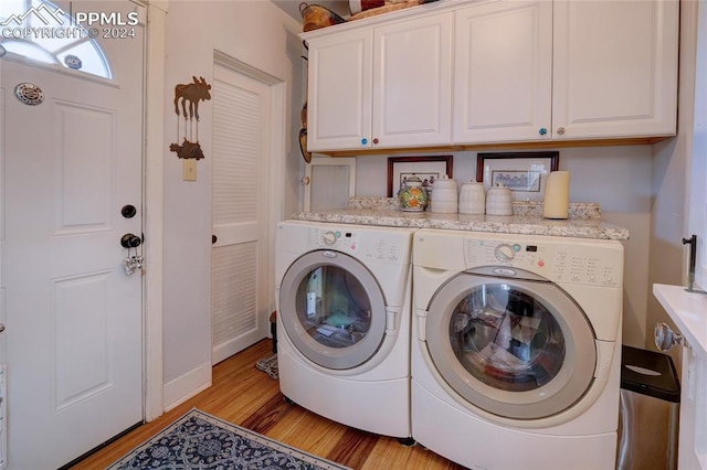 laundry area featuring light hardwood / wood-style flooring, washer and dryer, and cabinets